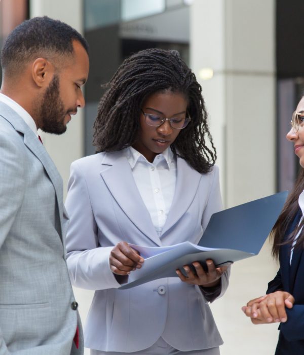 Confident friendly diverse business people discussing agreement in office hall. Business man and women standing in hallway, talking and reading document. Agreement concept